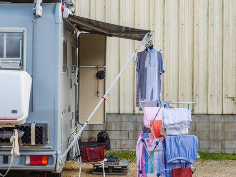 Clothes hang on a line near a recreational vehicle parked beside a building at a campsite