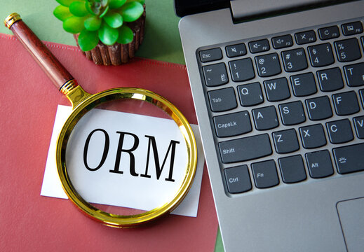 ORM - acronym on a white sheet under a magnifying glass next to a laptop