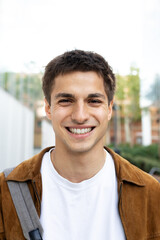 Fototapeta premium Portrait of smiling young man wearing brown jacket and backpack