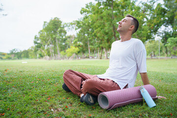 Obraz premium Peaceful man practicing yoga and meditation in green park