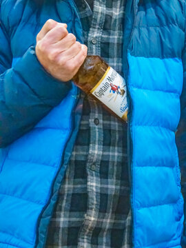 St Neots, UK - Friday 19th December 2025: A shoplifter putting a bottle of Captain Morgan Rum into his coat 