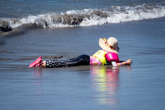 Child lying in the sand, just above the waves, on the beach in the Bocagrande area of Cartagena, Colombia