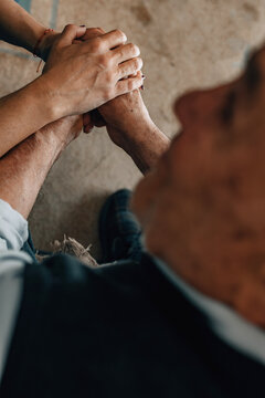 elderly couple tenderly holding hands, a gesture of emotional support, love, connection, and care between older people indoors