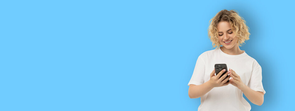 Woman smiles while using smartphone in a bright space