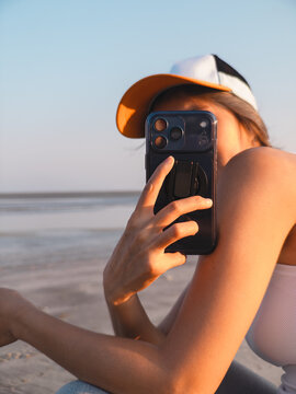 Relaxed woman taking spontaneous beach photograph at sunset