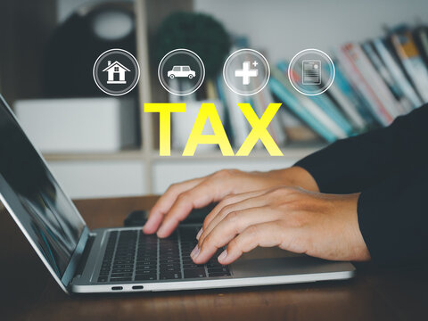 Person typing on laptop calculating tax obligations with financial icons and paperwork visible, professional concept showing online tax filing and financial planning