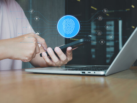 Fingerprint security authentication on smartphone with laptop in workspace, secure biometric login protecting data and privacy in modern office environment