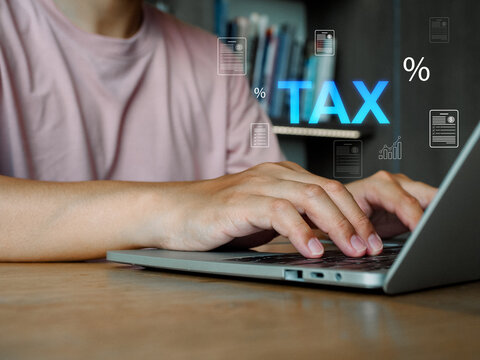 Person typing tax documents on laptop with percent icons and document graphics, focused hands and home office atmosphere