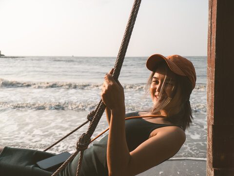 Joyful coastal swing. Relaxed woman enjoying breezy ocean moment