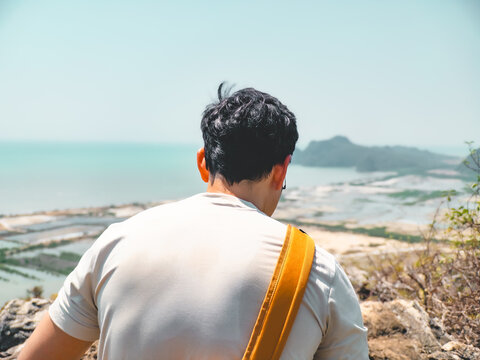 Person standing on rocky cliff observing expansive ocean scenery