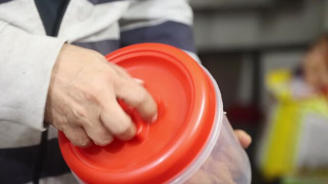 Raw 4K footage of a hand opening a plastic container lid, showing daily storage usage, simple kitchen routine, and practical household activity in an indoor setting.