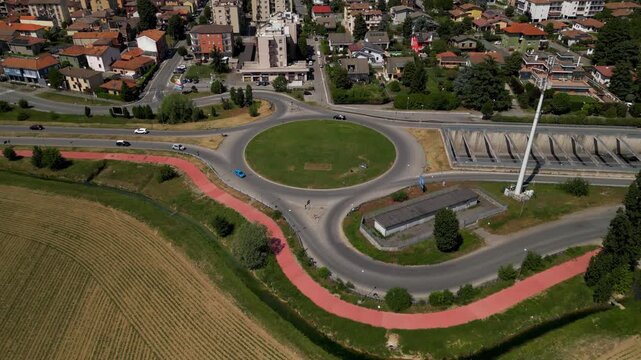 Aerial Roundabout Cityscape: A modern roundabout gracefully directs traffic amidst a bustling cityscape. The image features architectural diversity and urban design.