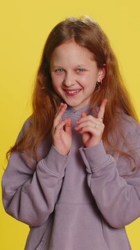 Sneaky cunning preteen child girl kid with tricky face gesticulating and scheming evil plan, thinking over devious villain idea, cheats, jokes, pranks. Teenager children isolated on yellow background