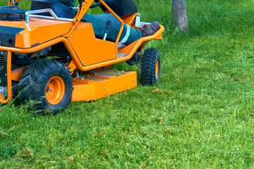 Obraz premium Professional grass cutting on lawns with a mini tractor lawn mower. 