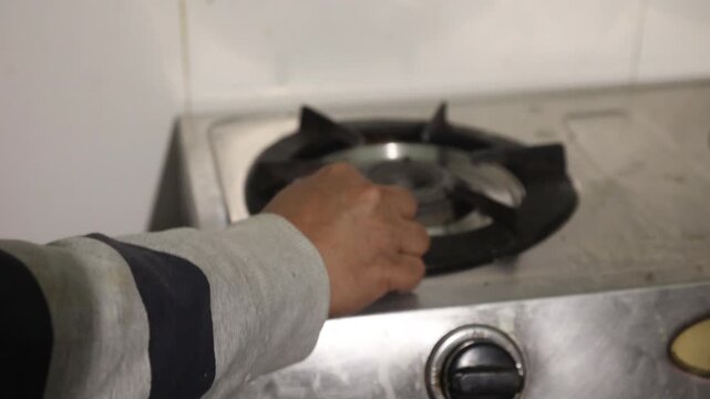 Raw 4K footage of a hand turning a gas stove knob, showing ignition process, daily cooking routine, and kitchen usage in a simple indoor household setting.