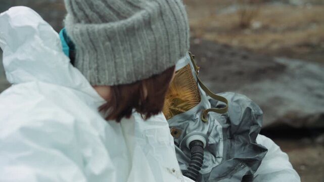 Caucasian child leaning toward masked rescuer, tight closeup shows exhausted faces with woolen hat and reflective visor, damp coast rocks in background, subtle relief and fear after contamination,