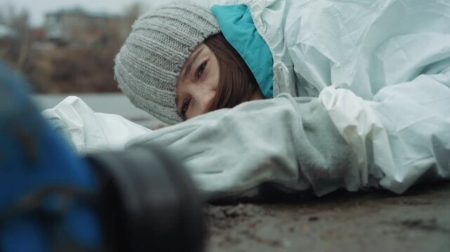 Caucasian survivor reaching for respirator on frozen ground, closeup of hand and mask, faint movement suggests hope, paramedic gear visible in blurred foreground, emergency evacuation hinted, teamwork