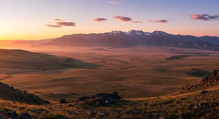 Naklejka premium Panoramic landscape of snow-capped mountains over a vast valley at sunset during golden hour