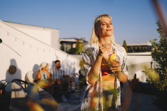 Blonde woman relaxing enjoying cocktail at rooftop party