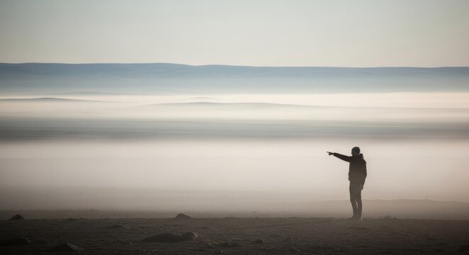 Person pointing towards vast misty horizon