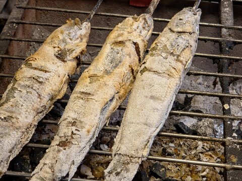 Traditional Thai Salt-Baked Grilled Snakehead Fish Cooking on a Charcoal Grill at a Street Food Market 