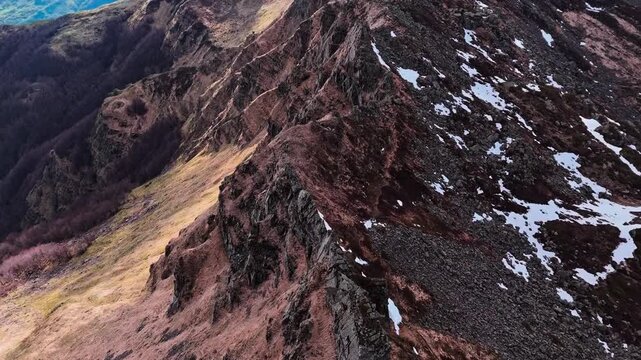 Aerial view of high mountain ridge with patches of snow during spring.