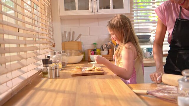 Little girl shaping dough in kitchen with parent nearby, representing learning, creativity, and childhood home cooking experience
