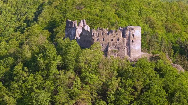 Scenic aerial footage of the medieval Sasovsky Castle ruins. The historic stone fortress is perched on a hilltop surrounded by a lush green forest