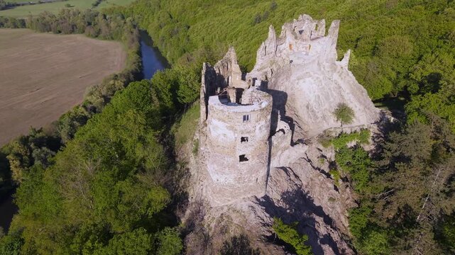 Drone shot flying over the medieval stone ruins of Sasovsky Castle in Slovakia. The ancient fortress sits on a rocky cliff above a river