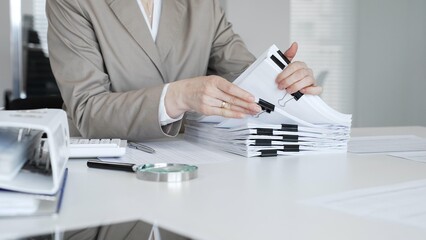 Fototapeta premium Businesswoman hands organizing financial documents stack on office desk, managing paperwork, bookkeeping, and administration. Audit and taxes concept