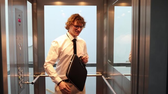 Office worker celebrates a successful result in the elevator with a briefcase and a joyful gesture showing victory relief confidence and excitement after work
