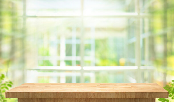 Selective focus.Wood table top,counter top with blur big glass wall and blur green bokeh