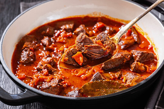 Spoon picking beef chunk from goulash stew