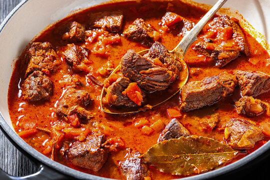 Spoon picking beef chunk from goulash stew