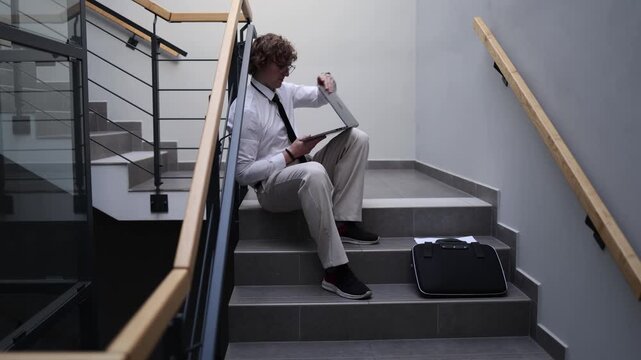 Ambitious worker continuing tasks after hours sitting on office stairs with laptop extra effort dedication to goals overtime mindset persistence career drive disciplined routine