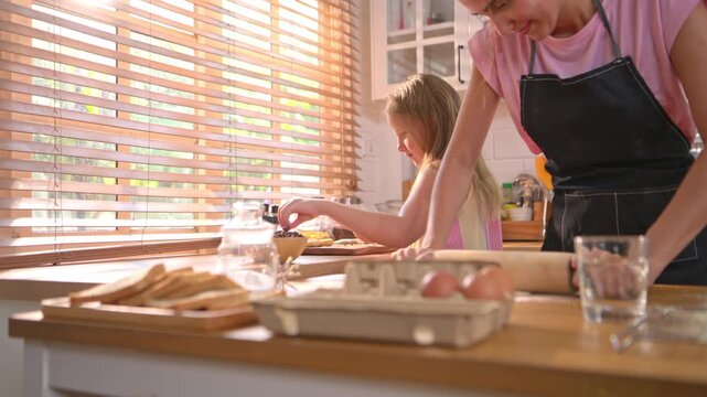 Little girl shaping dough in kitchen with parent nearby, representing learning, creativity, and childhood home cooking experience