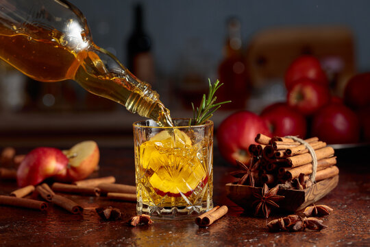 Apple kombucha is poured from a bottle into a crystal glass.