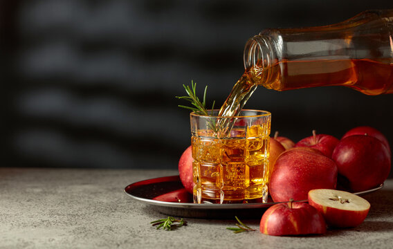 Apple juice is poured from a bottle into a glass.