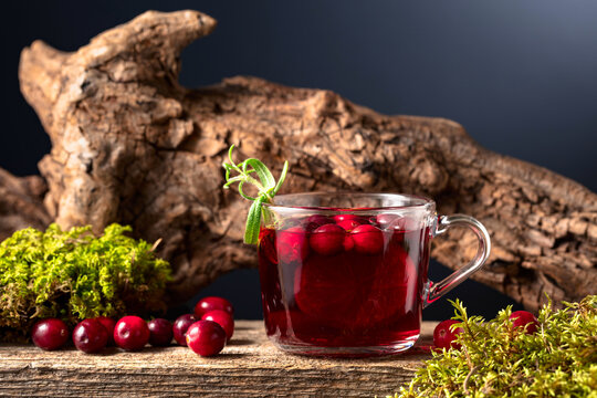 Hot drink with cranberries, lime, and rosemary on a old wooden board.