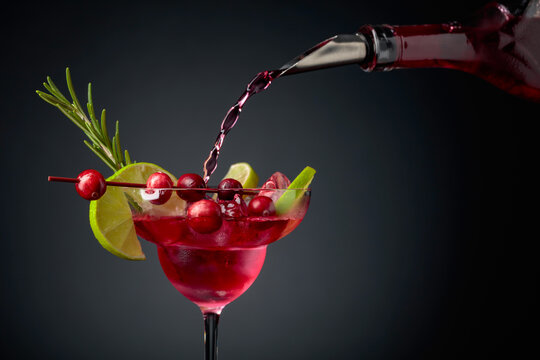 Cranberry cocktail garnished with berries, lime, and rosemary.