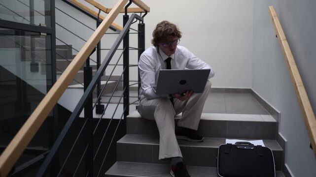 Job candidate preparing for interview reviewing notes on laptop focused mindset rehearsing answers planning career move quiet stairwell study moment determination and confidence growth