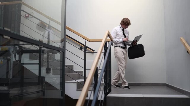 Multitasking professional working while walking down stairs checking laptop on the move fast paced routine constant connectivity modern hustle efficiency in motion business lifestyle