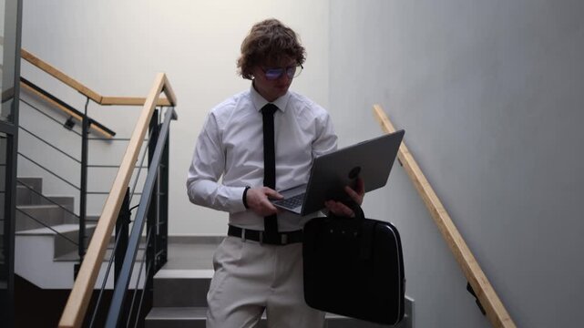Office worker leaving workplace walking downstairs with laptop and briefcase end of workday transition commuting routine focused professional moving between tasks daily rhythm corporate life