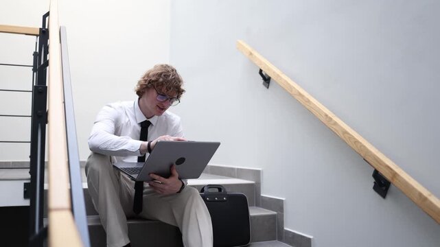 Freelancer taking break on stairway working remotely with laptop relaxed posture informal workspace outside office routine digital nomad mindset flexible schedule modern independence
