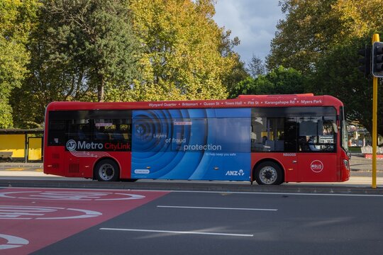 AUCKLAND, NEW ZEALAND &ndash; May 2, 2026: A red Metro CityLink bus with an advertisement for ANZ bank's fraud protection, travels along a city street in Auckland.