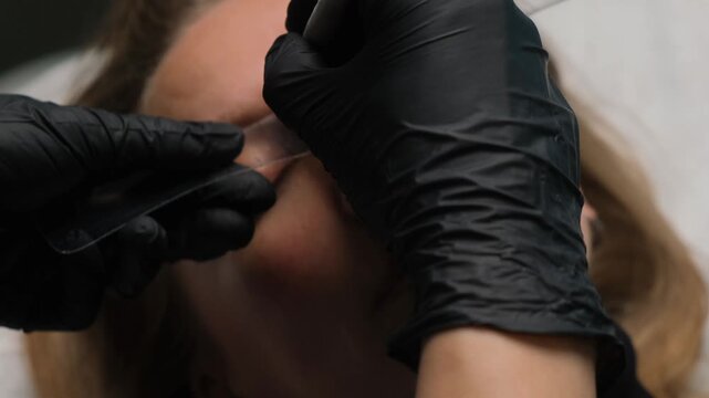 Permanent makeup artist preparing a client's eyebrows for a cosmetic tattooing procedure