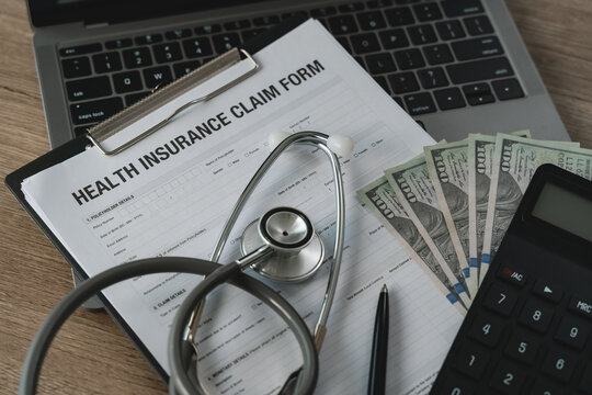 Stethoscope placed on health insurance claim form with cash and calculator on desk, representing medical expense calculation, insurance claim process, healthcare cost management, and financial coverag