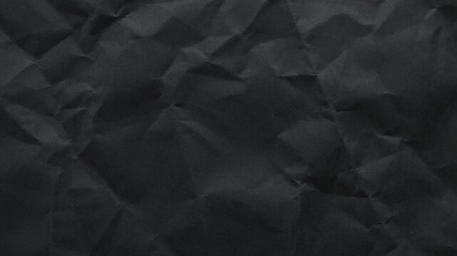 High-quality black wrinkled paper texture animation. Seamless loop with stop-motion effect, perfect for dark minimal backgrounds and video overlays.