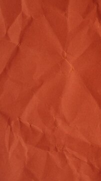 Vertical stop-motion animation of orange wrinkled paper. Seamless loop for warm mobile-friendly backgrounds and creative vertical content.