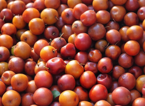 A vibrant top-down close-up of fresh red and orange Indian Jujube fruits, traditionally known as Bhogi Pallu or Regi Pallu, used in Hindu festival rituals.